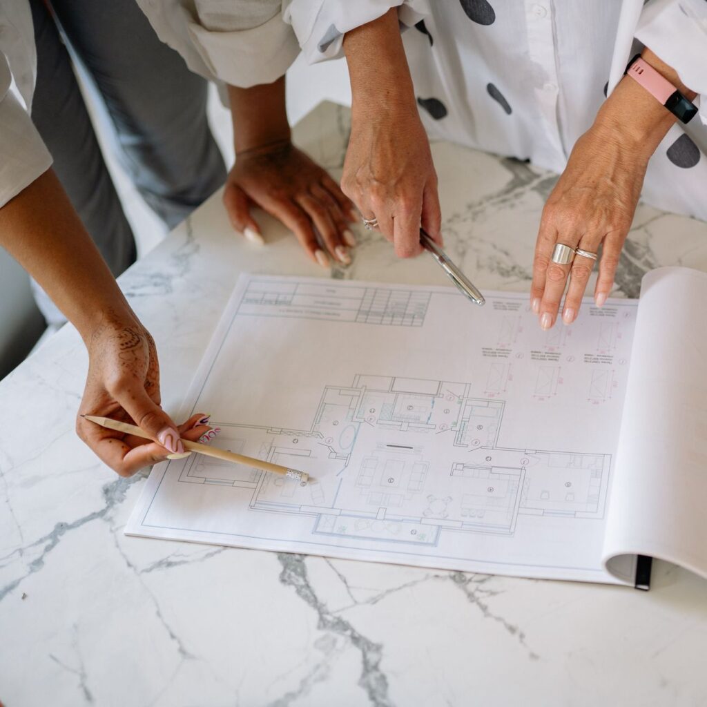 women pointing at blueprint of house